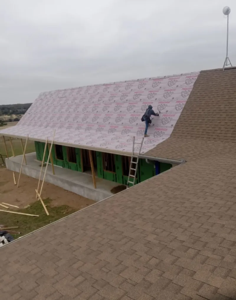 Worker preparing underlayment for a metal roof installation in Hingham